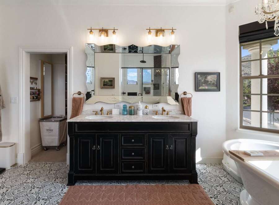 Experience luxury in this stunning bathroom featuring a double vanity with marble countertops and ornate mirrors.
