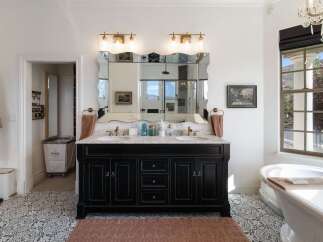 Experience luxury in this stunning bathroom featuring a double vanity with marble countertops and ornate mirrors.