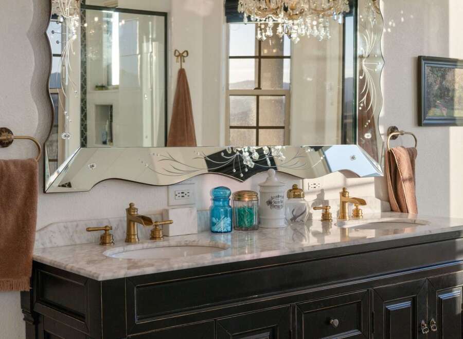 Indulge in luxury with this elegant bathroom vanity featuring a marble countertop and a decorative mirrored backsplash.