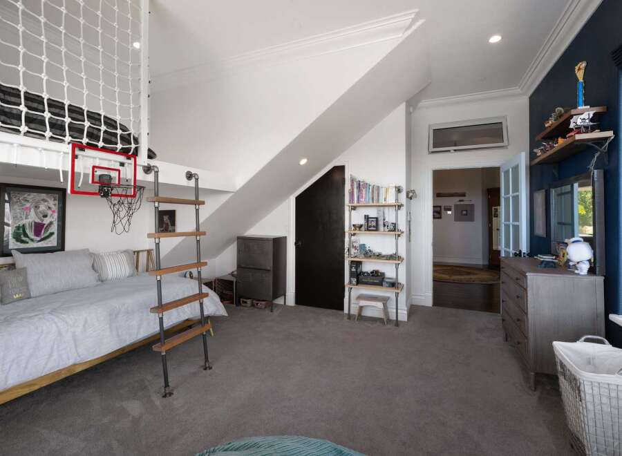 This unique bedroom features a lofted bed with a playful basketball hoop and ladder, perfect for a child's or teen's space.
