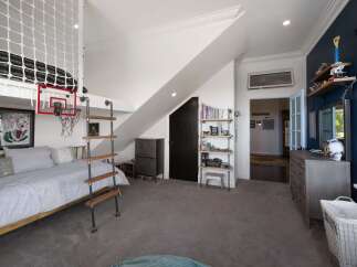This unique bedroom features a lofted bed with a playful basketball hoop and ladder, perfect for a child's or teen's space.