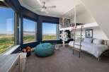 Experience breathtaking panoramic views from this stunning bedroom, featuring expansive windows that showcase a vibrant cityscape and rolling hills.