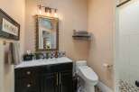 This charming bathroom features a modern black vanity with gold hardware, complemented by a decorative tiled backsplash.