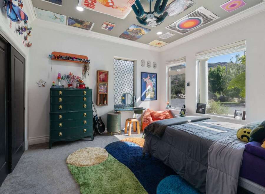 This eclectic bedroom features a vibrant green dresser adorned with gold hardware, complemented by a collection of colorful rugs on the floor.