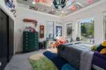 This eclectic bedroom features a vibrant green dresser adorned with gold hardware, complemented by a collection of colorful rugs on the floor.