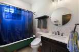 This charming bathroom features a vibrant green clawfoot bathtub paired with a striking blue shower curtain, creating a unique focal point.