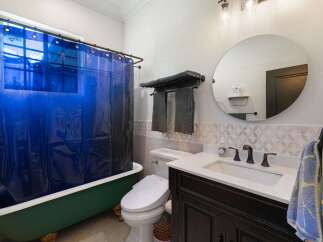 This charming bathroom features a vibrant green clawfoot bathtub paired with a striking blue shower curtain, creating a unique focal point.