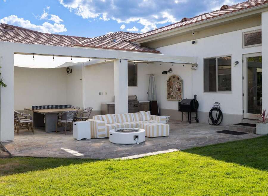 Enjoy outdoor living at its finest with this expansive patio featuring a comfortable sectional sofa, a modern fire pit, and a dining area perfect for al fresco meals.