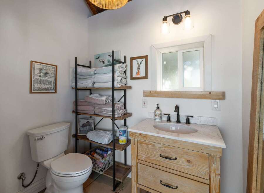 This charming bathroom features a rustic wooden vanity with a marble countertop, complemented by a sleek black faucet and a white undermount sink.