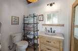 This charming bathroom features a rustic wooden vanity with a marble countertop, complemented by a sleek black faucet and a white undermount sink.