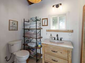 This charming bathroom features a rustic wooden vanity with a marble countertop, complemented by a sleek black faucet and a white undermount sink.