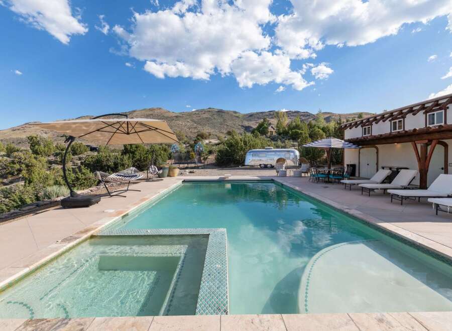 Experience ultimate relaxation in this stunning backyard oasis featuring a sparkling swimming pool and integrated spa, perfect for unwinding under the vast blue sky.