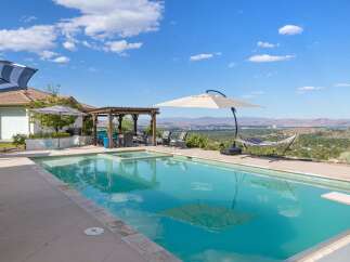 Enjoy breathtaking panoramic views from this stunning backyard oasis, complete with a sparkling swimming pool and integrated spa.