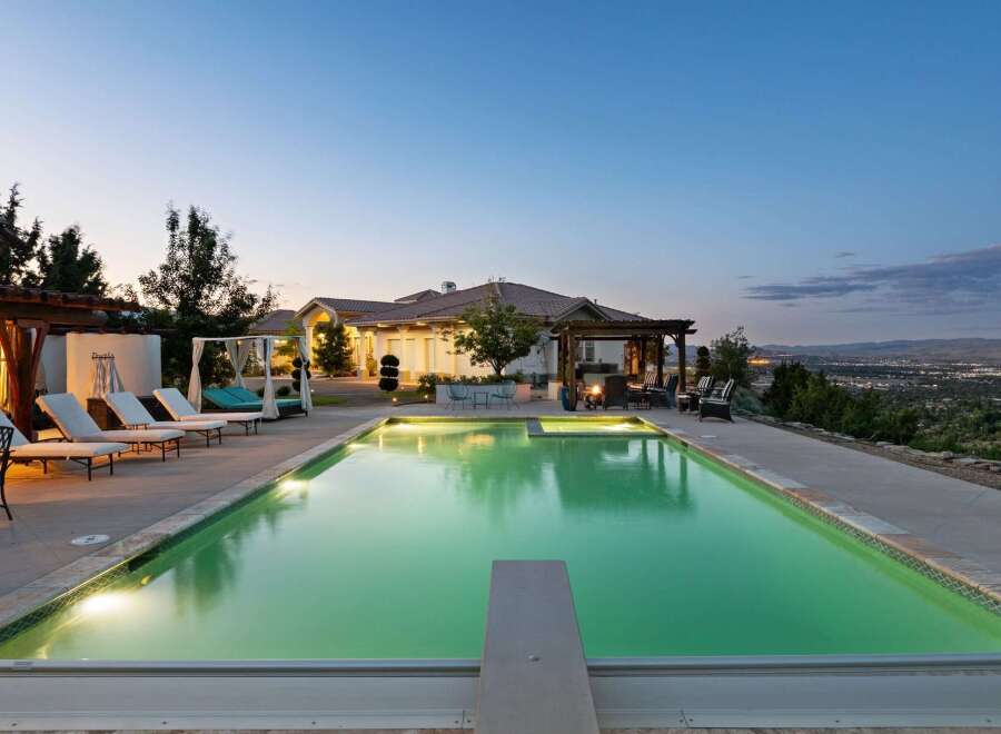 Experience luxury living with this stunning property featuring a large, illuminated swimming pool and a relaxing spa area.