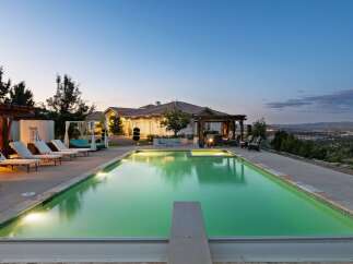 Experience luxury living with this stunning property featuring a large, illuminated swimming pool and a relaxing spa area.