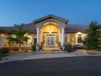 This stunning residence features a grand arched entryway with elegant columns, leading to double doors and large windows that illuminate the interior.