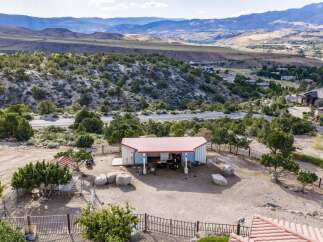 Discover this unique property featuring a charming barn with a red roof, perfect for housing animals or as a versatile workshop space.