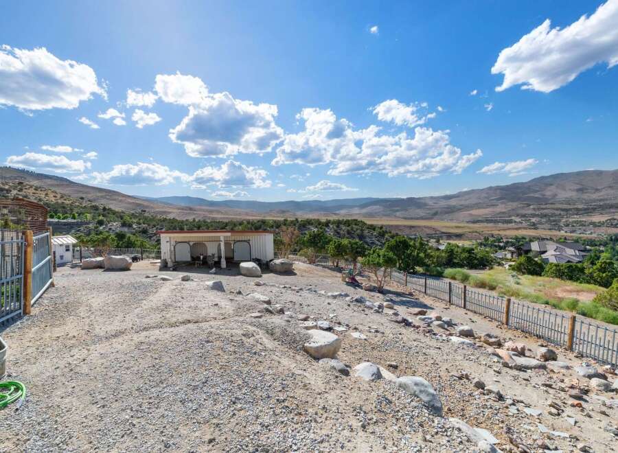 Discover this unique property featuring a spacious open-air shelter perfect for animals, complemented by a fenced enclosure and a scenic view of the surrounding valley.