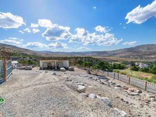 Discover this unique property featuring a spacious open-air shelter perfect for animals, complemented by a fenced enclosure and a scenic view of the surrounding valley.