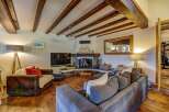 Experience rustic charm in this inviting living room, featuring exposed wooden beams and a cozy stone fireplace perfect for chilly evenings.