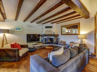 Experience rustic charm in this inviting living room, featuring exposed wooden beams and a cozy stone fireplace perfect for chilly evenings.