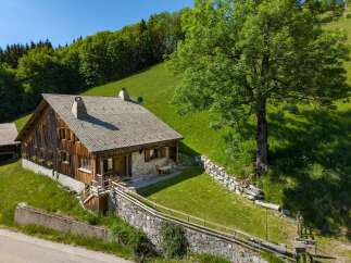 Nestled on a lush green hillside, this charming wooden chalet offers a serene mountain retreat.
