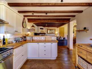 Experience rustic charm in this beautifully appointed kitchen, featuring exposed wooden beams and a cozy, country-style aesthetic.