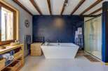 Experience rustic charm and modern luxury in this stunning bathroom, featuring a deep soaking tub and a spacious glass-enclosed shower.