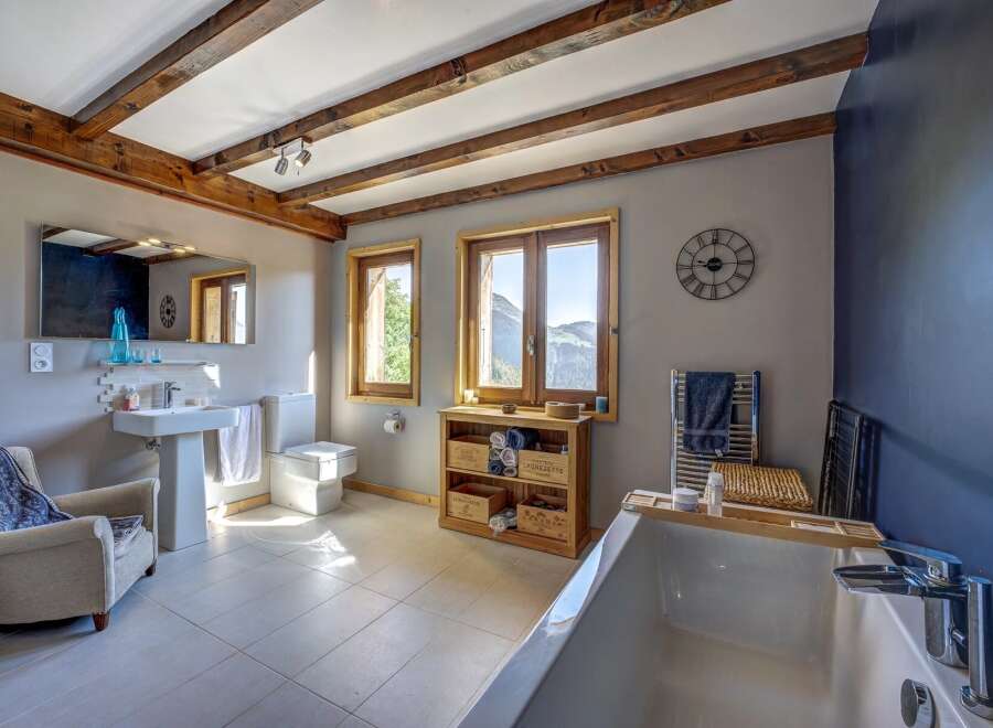 Experience rustic charm and modern comfort in this stunning bathroom, featuring exposed wooden beams and a luxurious bathtub with a view.