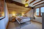 Experience cozy mountain living in this charming attic bedroom, featuring a rustic wooden ceiling and exposed beams.