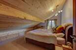 Experience cozy mountain living in this charming attic bedroom, featuring a sloped wooden ceiling and built-in storage.