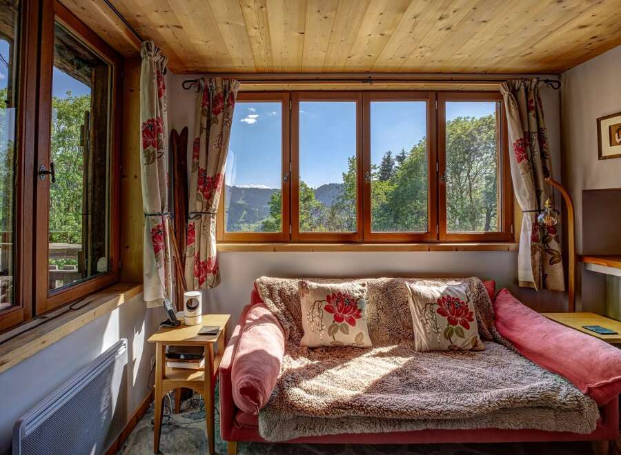 Experience breathtaking mountain views from this cozy living space, featuring a comfortable sofa adorned with floral pillows and a plush throw.