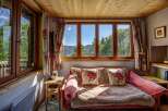 Experience breathtaking mountain views from this cozy living space, featuring a comfortable sofa adorned with floral pillows and a plush throw.
