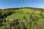 Discover this charming property nestled in a serene mountain landscape, featuring traditional wooden chalets surrounded by lush green meadows and dense pine forests.