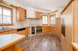 This charming kitchen features warm wooden cabinetry and a tiled backsplash, creating a cozy and inviting atmosphere.