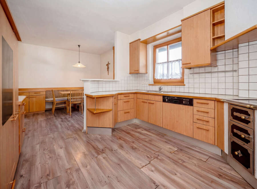 Discover this charming kitchen featuring warm wooden cabinetry and a cozy dining nook.