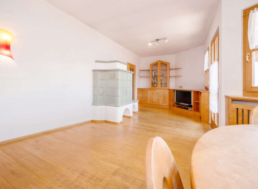 Experience cozy living in this charming room featuring a traditional tiled stove, perfect for warming up on cold evenings.