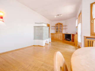 Experience cozy living in this charming room featuring a traditional tiled stove, perfect for warming up on cold evenings.