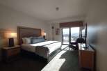 Experience comfort and stunning views in this hotel room, featuring a plush king-sized bed and a private balcony overlooking a scenic landscape.