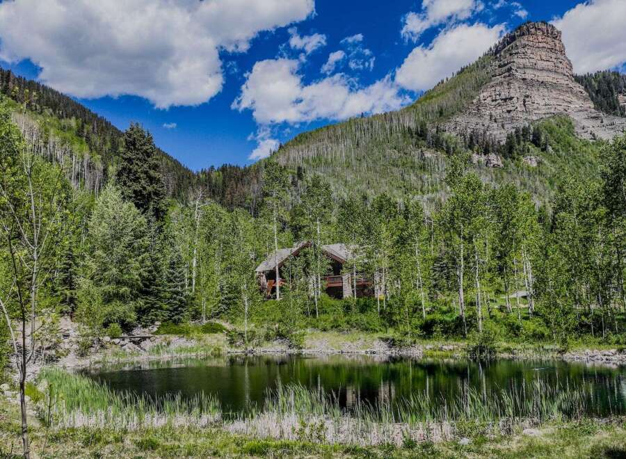 Escape to this secluded mountain retreat, featuring a charming log cabin nestled amidst a serene forest and a tranquil pond.