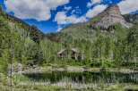 Escape to this secluded mountain retreat, featuring a charming log cabin nestled amidst a serene forest and a tranquil pond.