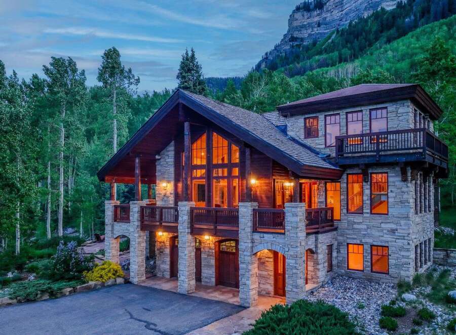 Experience luxury mountain living in this stunning stone and timber lodge nestled amidst a serene forest.