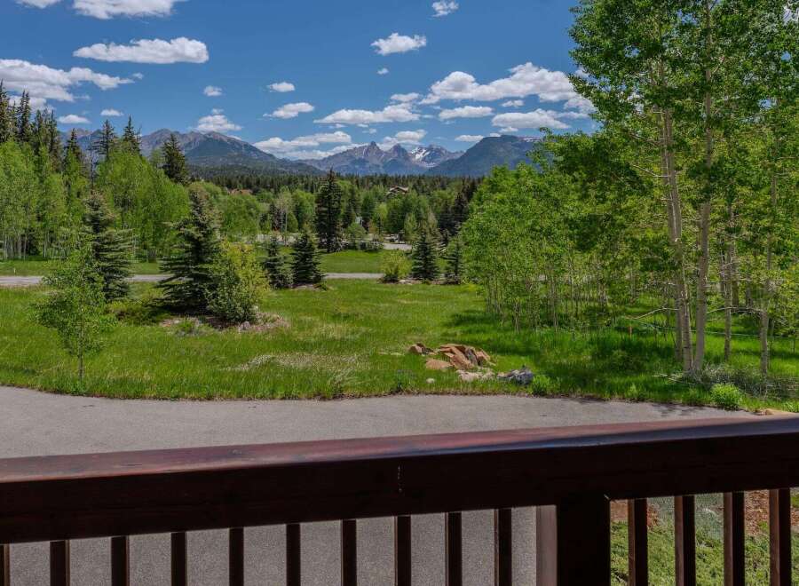 Experience breathtaking mountain views from this stunning property, surrounded by lush green trees and vibrant blue skies.