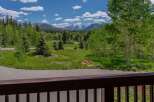 Experience breathtaking mountain views from this stunning property, surrounded by lush green trees and vibrant blue skies.