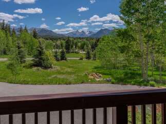 Experience breathtaking mountain views from this stunning property, surrounded by lush green trees and vibrant blue skies.