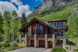 Experience luxury mountain living in this stunning stone and timber home, nestled against a dramatic cliff face and surrounded by lush greenery.