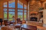 Experience breathtaking mountain views from this stunning living room, featuring a grand stone fireplace and expansive windows.