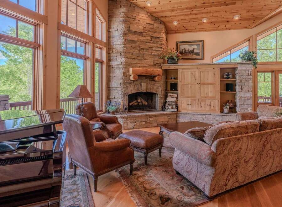 Experience luxury living in this stunning great room, featuring a grand stone fireplace and soaring windows that flood the space with natural light.