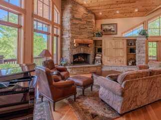 Experience luxury living in this stunning great room, featuring a grand stone fireplace and soaring windows that flood the space with natural light.