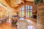 Experience rustic elegance in this stunning living room, featuring a grand stone fireplace and soaring vaulted ceilings with exposed wood beams.